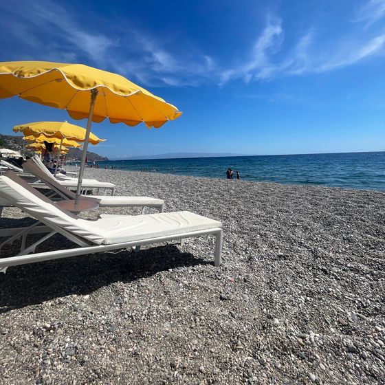 Yellow umbrellas and white loungers on a pebble beach by the sea